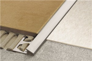 Schluter-RENO-U is a reducing profile designed to provide a smooth transition between tile coverings and floor coverings at lower elevations or finished concrete. RENO-U features a trapezoid-perforated anchoring leg, which is secured in the mortar bond coat beneath the tile, and a sloped surface (approximately 25 degrees) that eliminates trip hazards and protects tile edges. The leading edge of the profile abuts the lower surface covering, typically VCT.