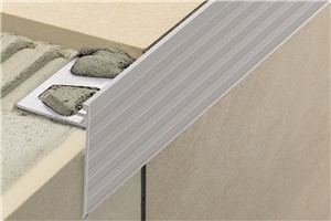 Schluter-SCHIENE-STEP is a finishing and edging profile for ceramic tile and natural stone installations on countertops, stairs, and tile over tile applications on walls. The profile features a trapezoid-perforated anchoring leg, which is secured in the mortar bond coat beneath the tile. The top of the profile features a vertical wall section that finishes and protects the tile from damage, while the vertical leg covers the edge of the subassembly, top of the riser, or existing wall tile edge.